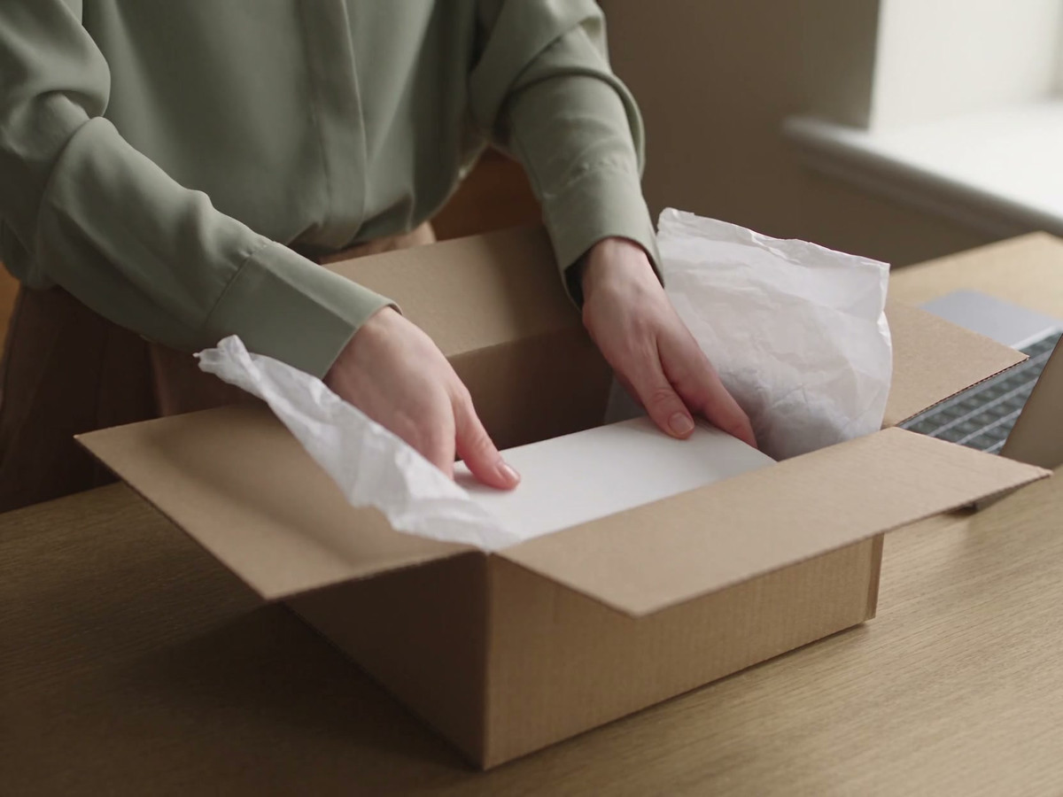 A clinic team member carefully packs skincare products into a parcel