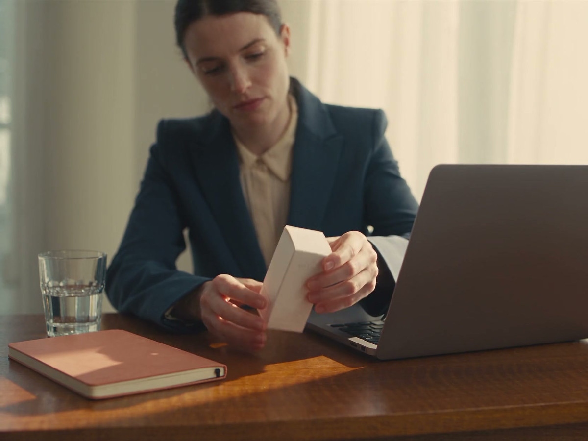 A clinic team member checks a skincare product beside a laptop