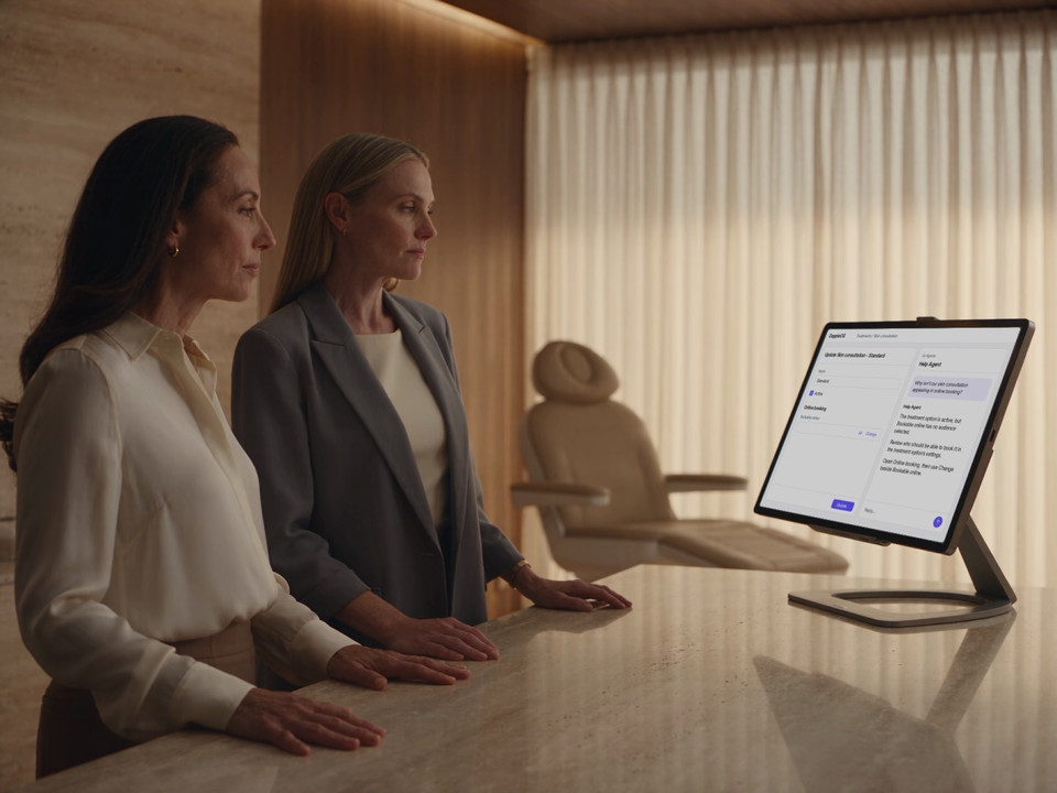 Two clinic colleagues review an online-booking setting beside Help Agent guidance.