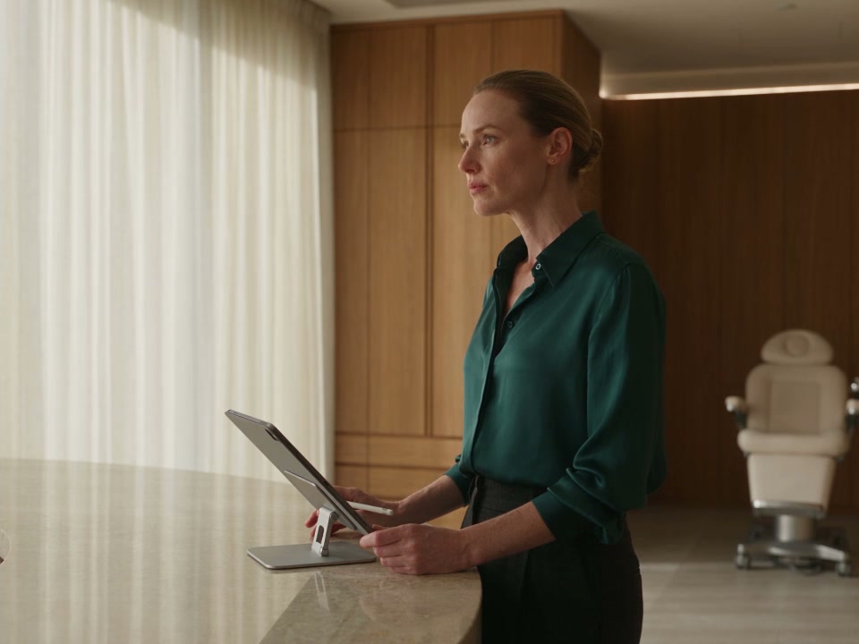 A clinic team member reviews information on a supported tablet at the desk, with its screen facing away