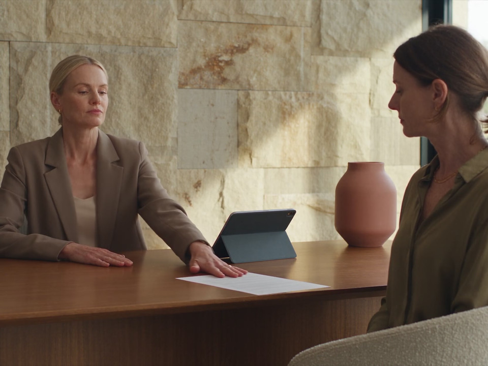 A clinic team member passes a prepared paper request to a patient at reception