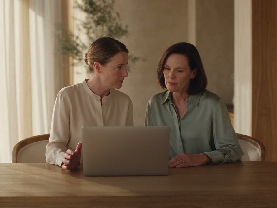 Illustrative clinic footage of two colleagues discussing a question together at a laptop.