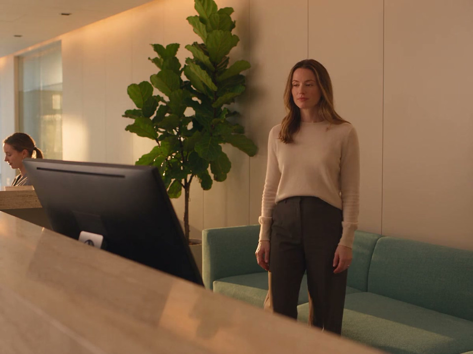 A clinic manager stops at a fixed workstation in a bright reception to review the location’s activity